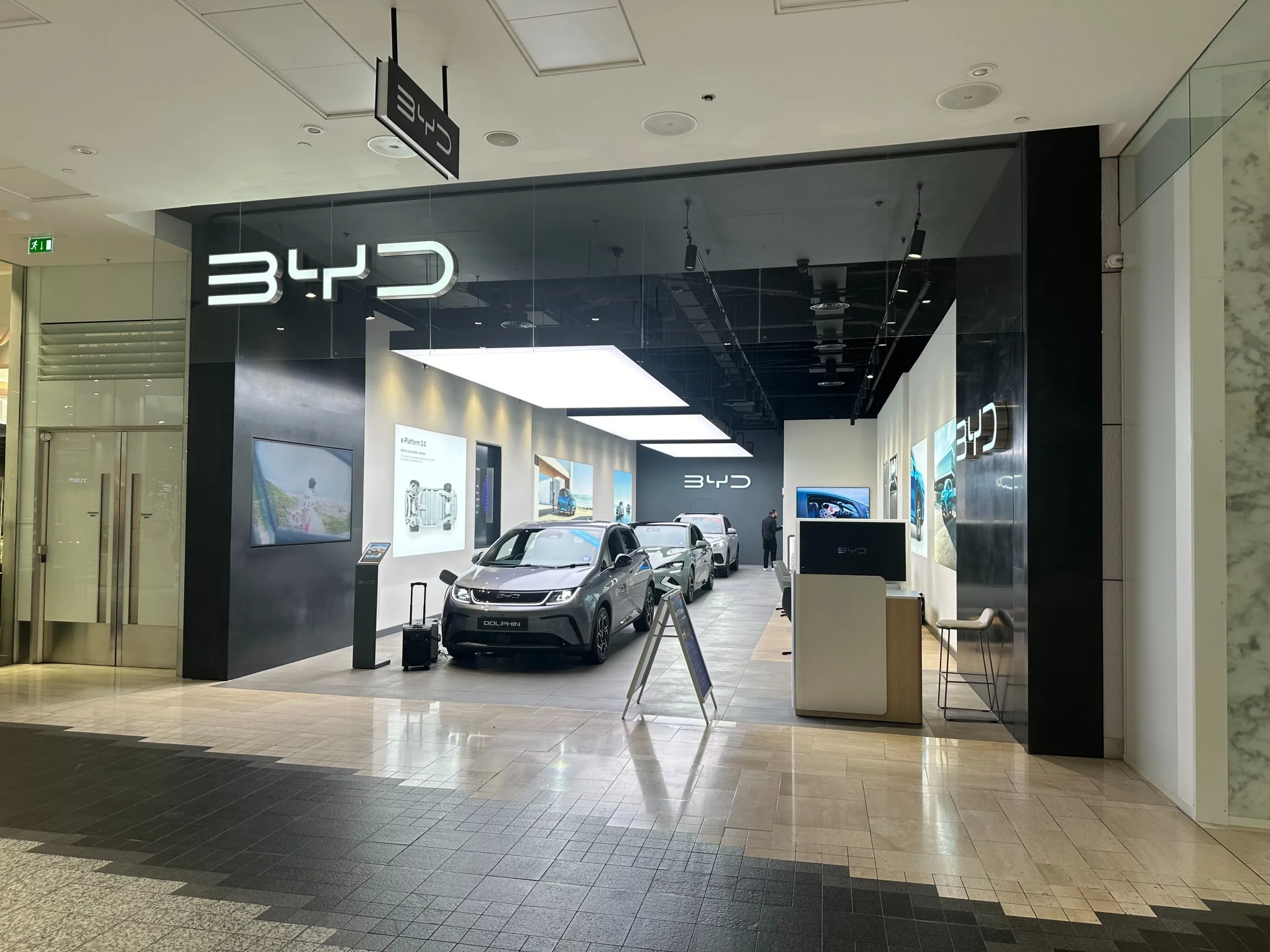 BYD car showroom in a shopping centre, with cars under a lightbox ceiling