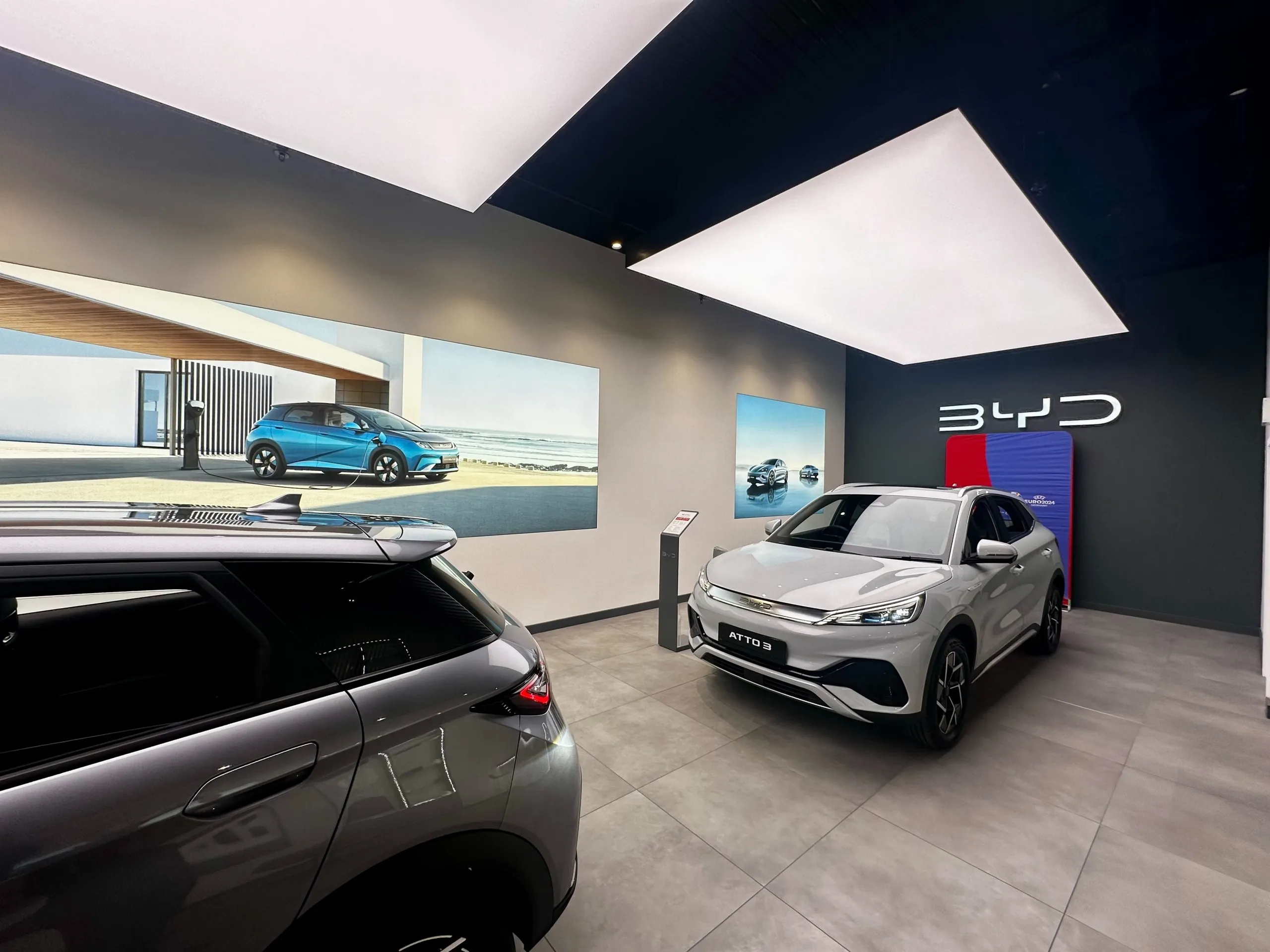BYD showroom with electric cars, brand graphics and lightbox ceiling