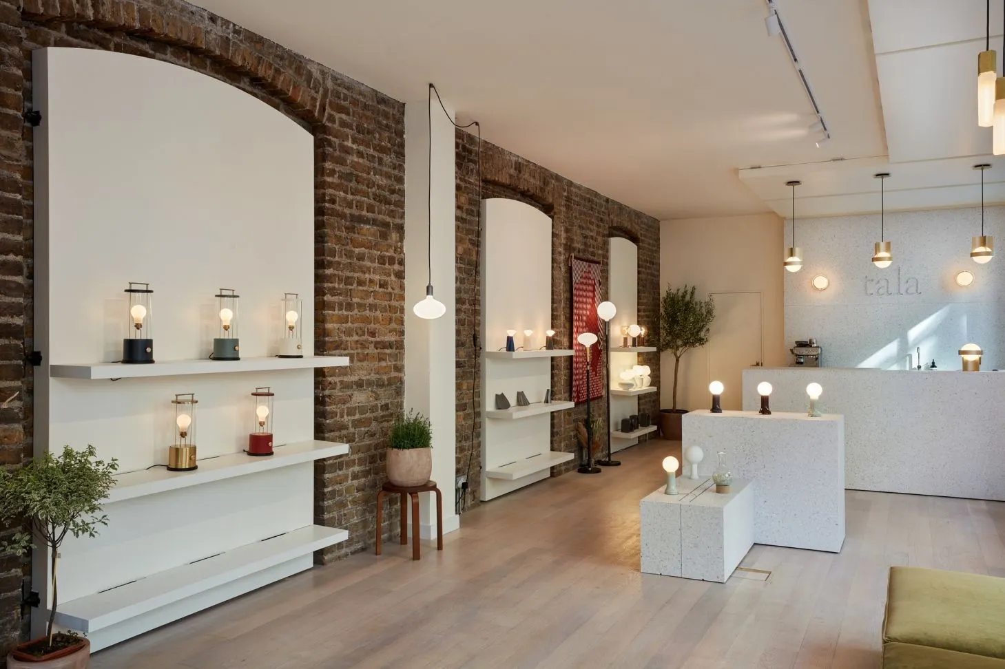 Tala showroom with lamps on white shelving against exposed brick arches
