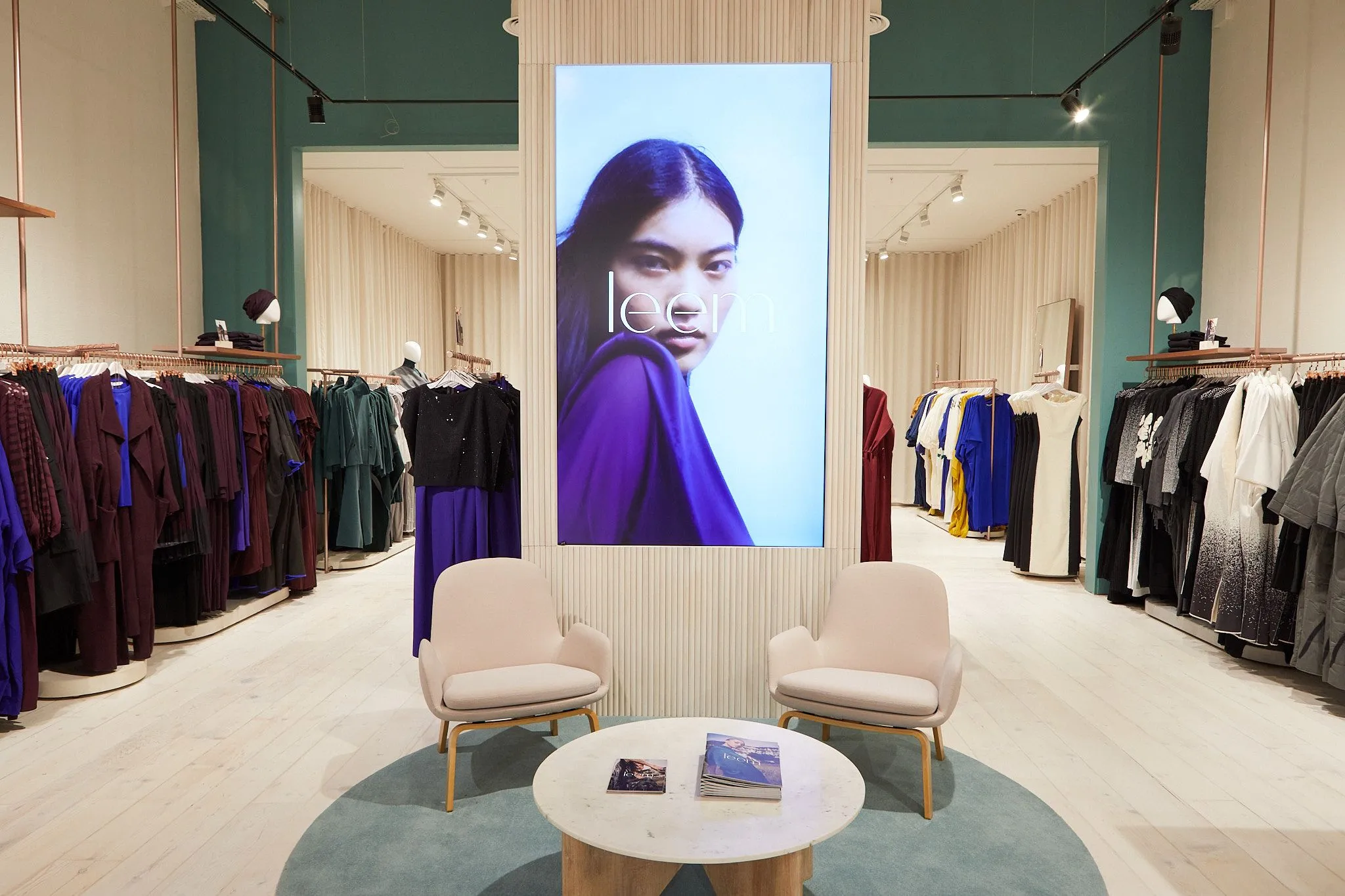Leem store with a digital screen, lounge chairs and rails of jewel-toned clothing