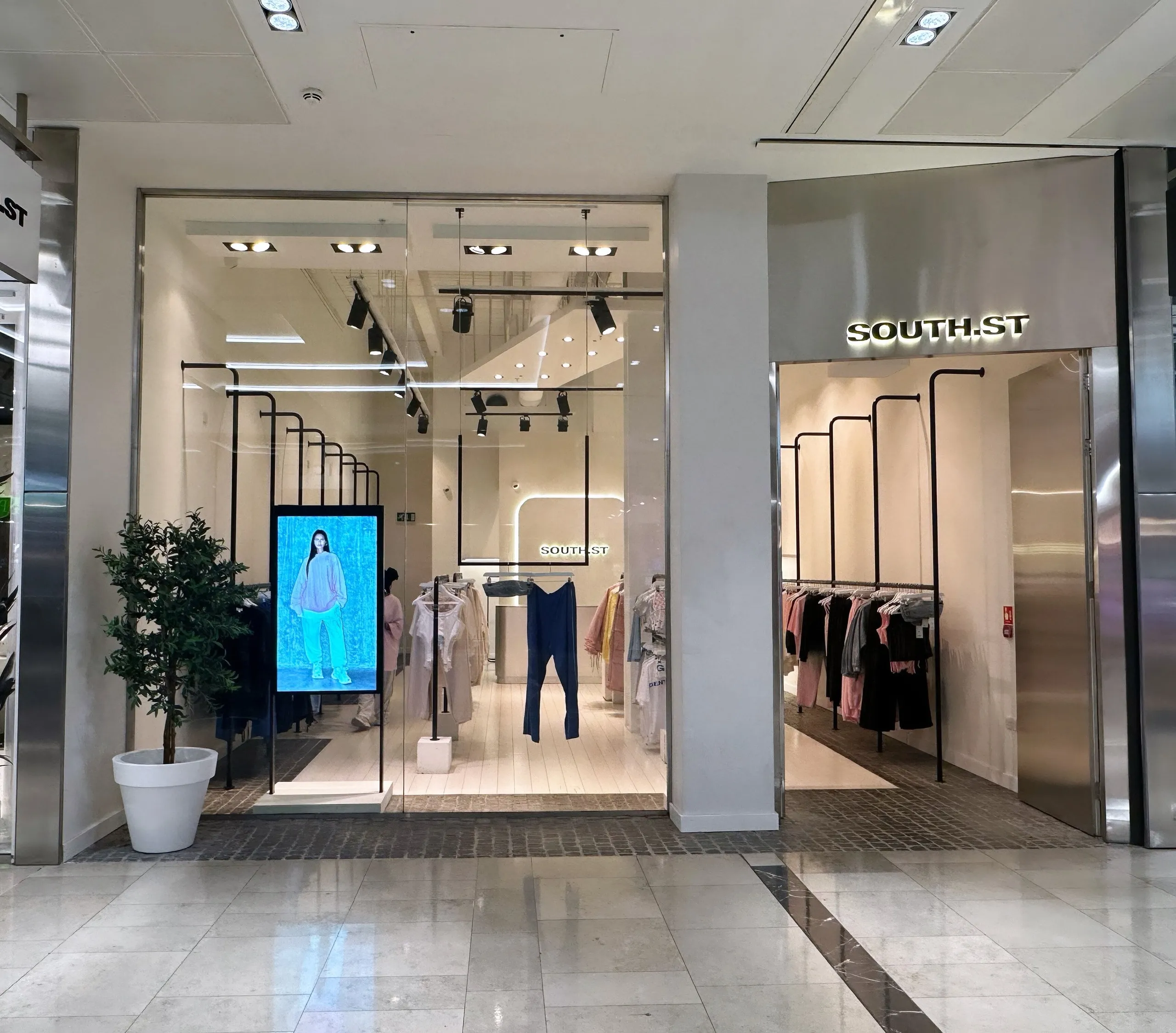 South.St store front in a shopping centre with a digital screen and clothing rails