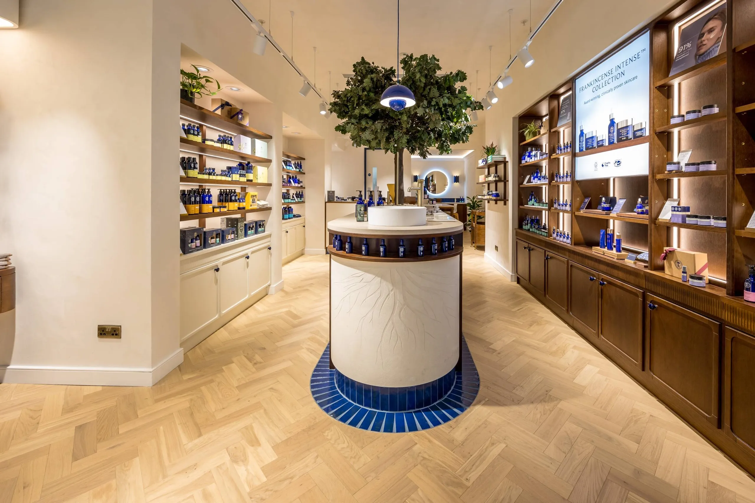 Neal's Yard Remedies store with timber shelving, herringbone floor and a central tree display