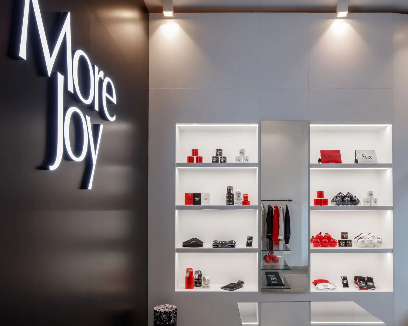 More Joy store with illuminated white shelving and a large backlit logo