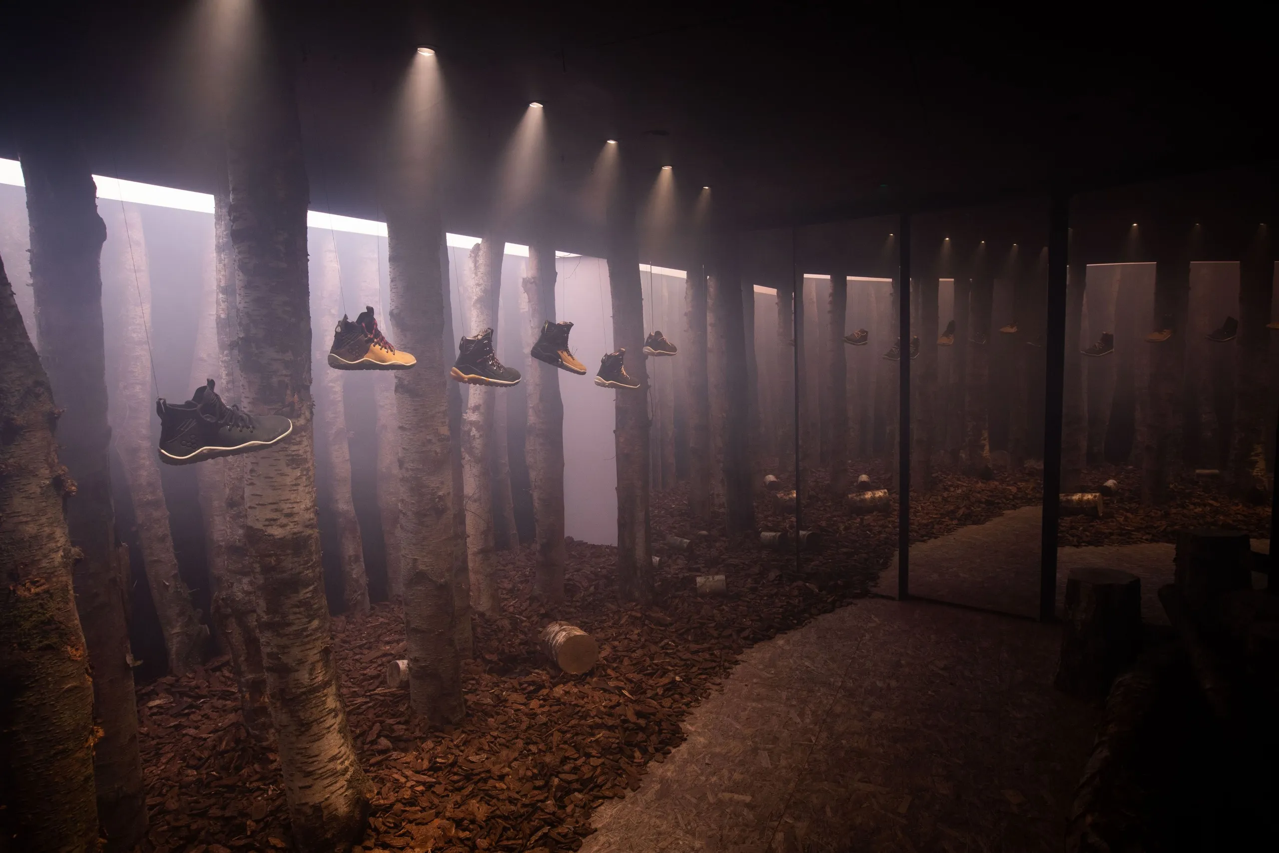 Immersive forest installation with trainers floating among tree trunks