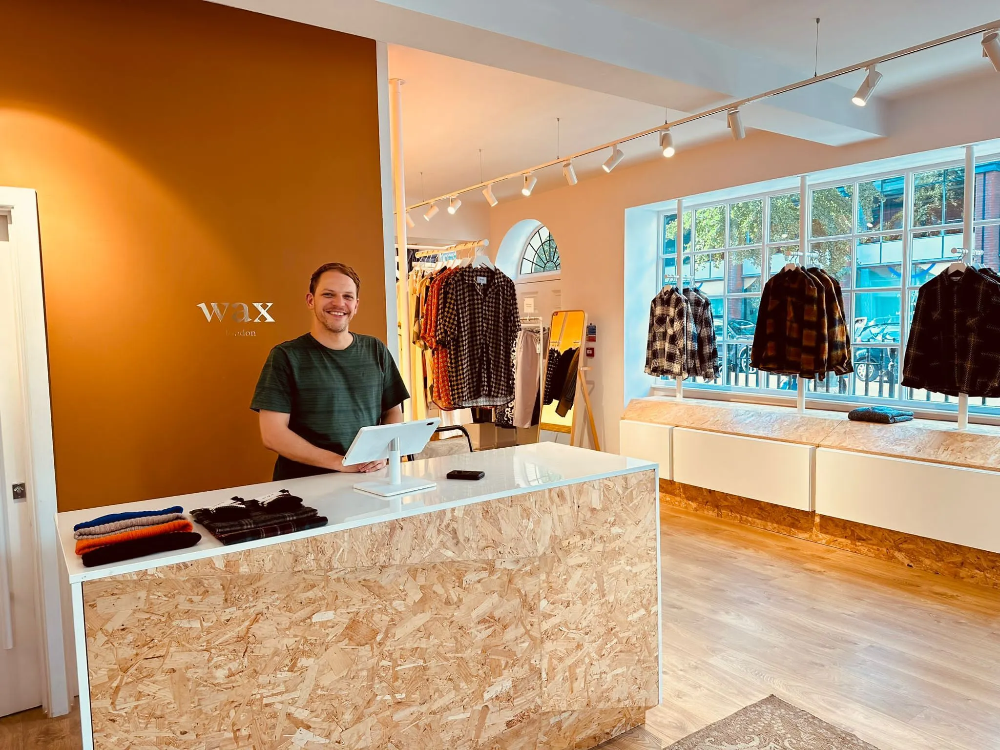 Wax London store with an OSB cash desk, terracotta wall and shirts on rails