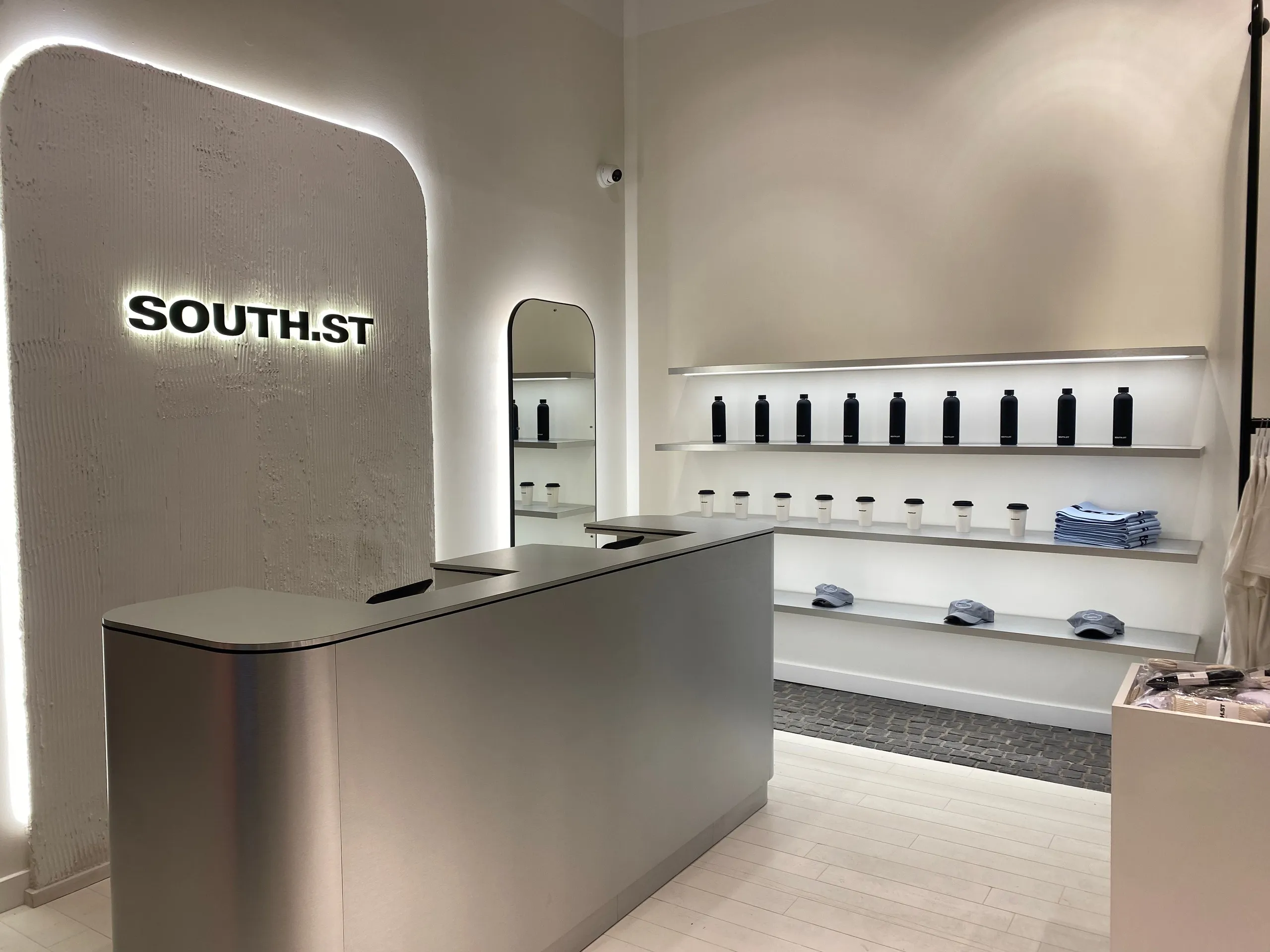South.St store with a brushed steel counter, backlit logo and illuminated shelving