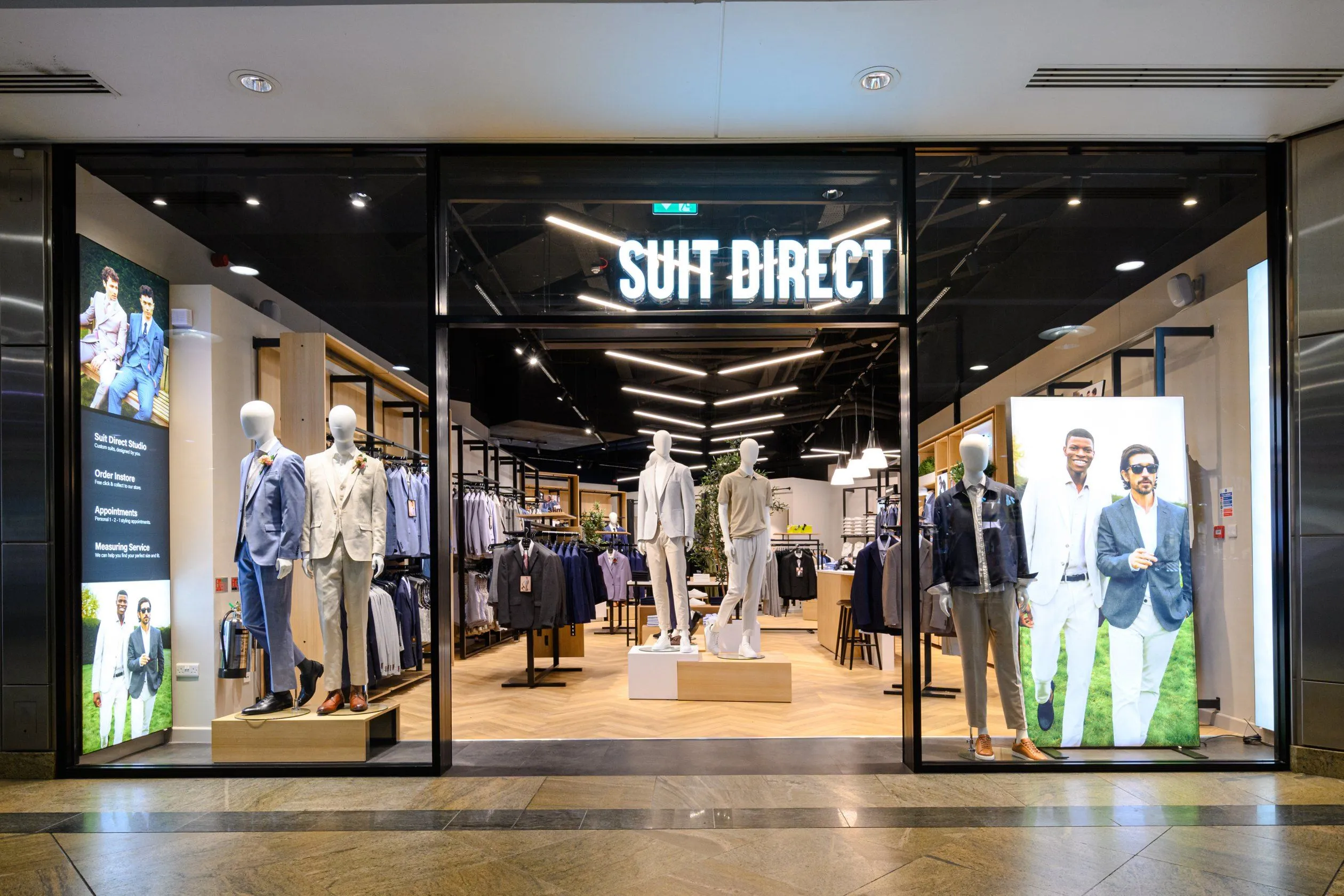 Suit Direct store front in a shopping centre with mannequins and backlit graphics