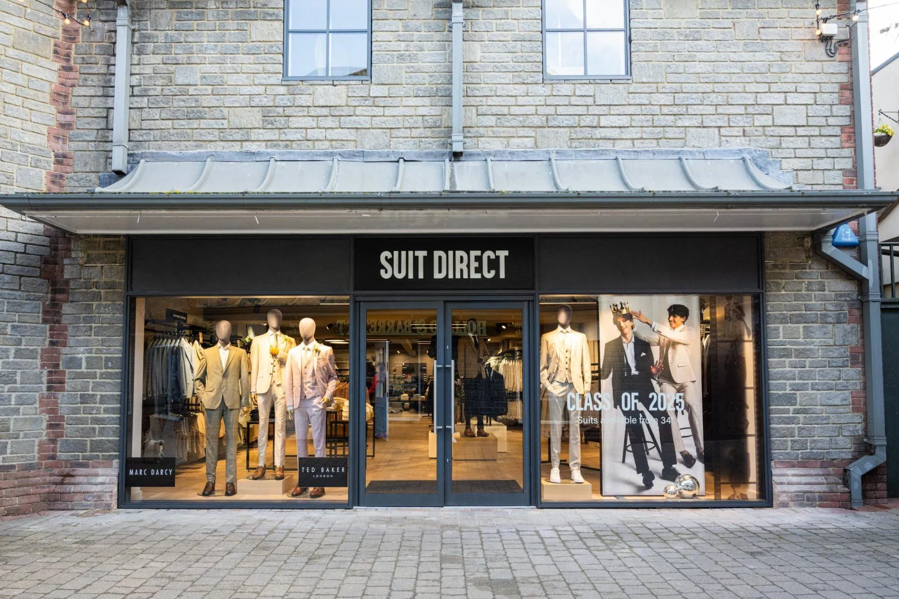 Suit Direct shopfront in a brick building, with mannequins in the windows