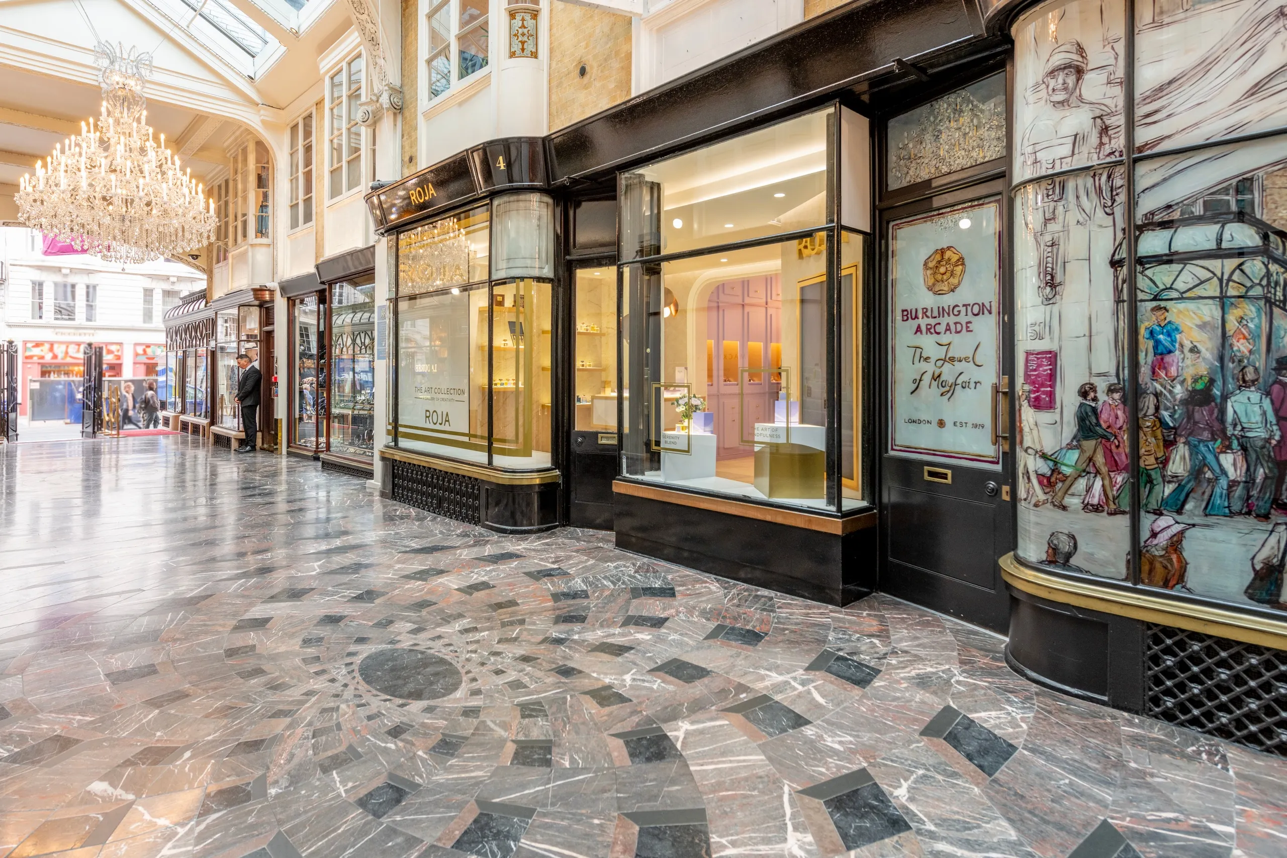 Roja boutique with brass pendant lights, a display plinth and an arch into the lilac room