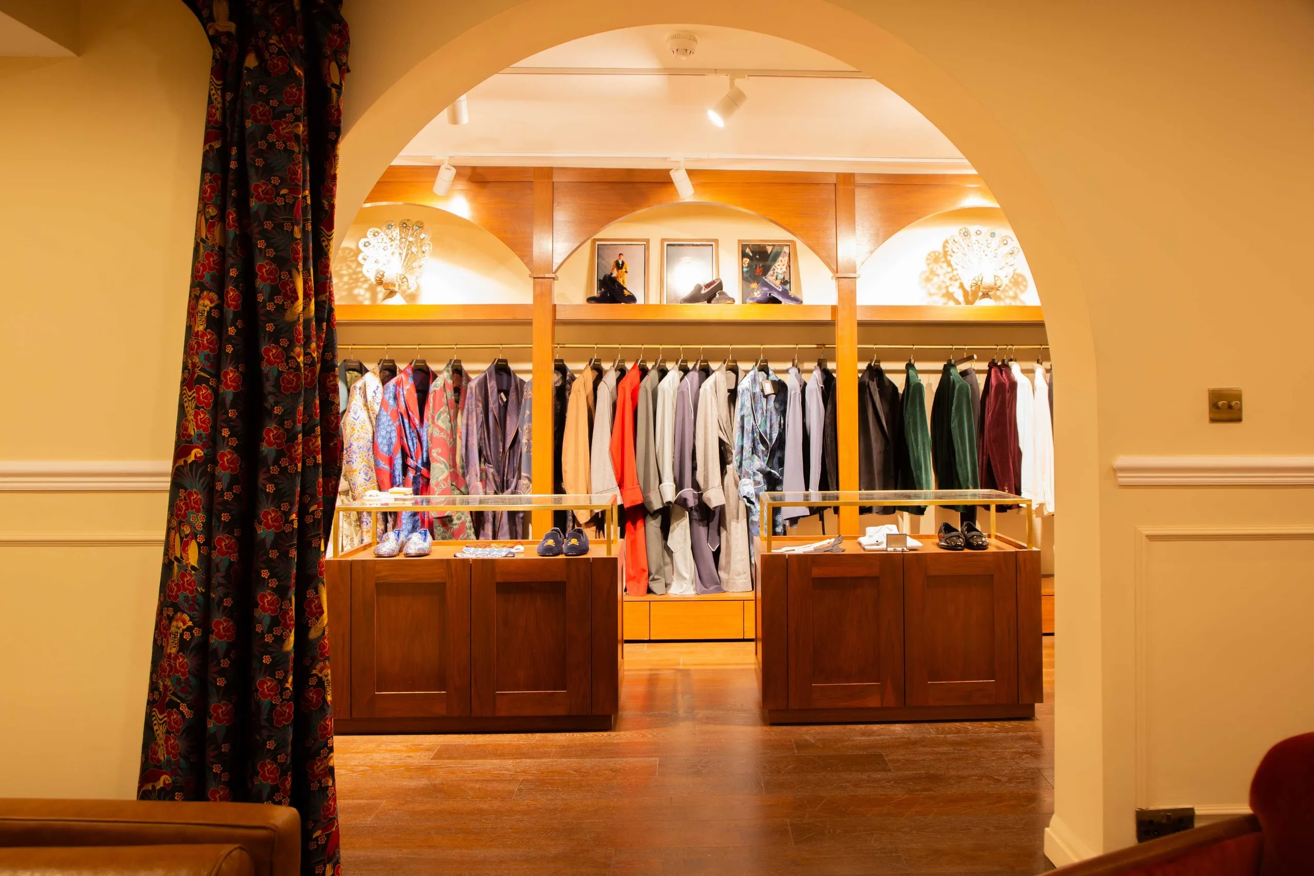 Menswear boutique seen through an arch, with timber counters and shirt rails