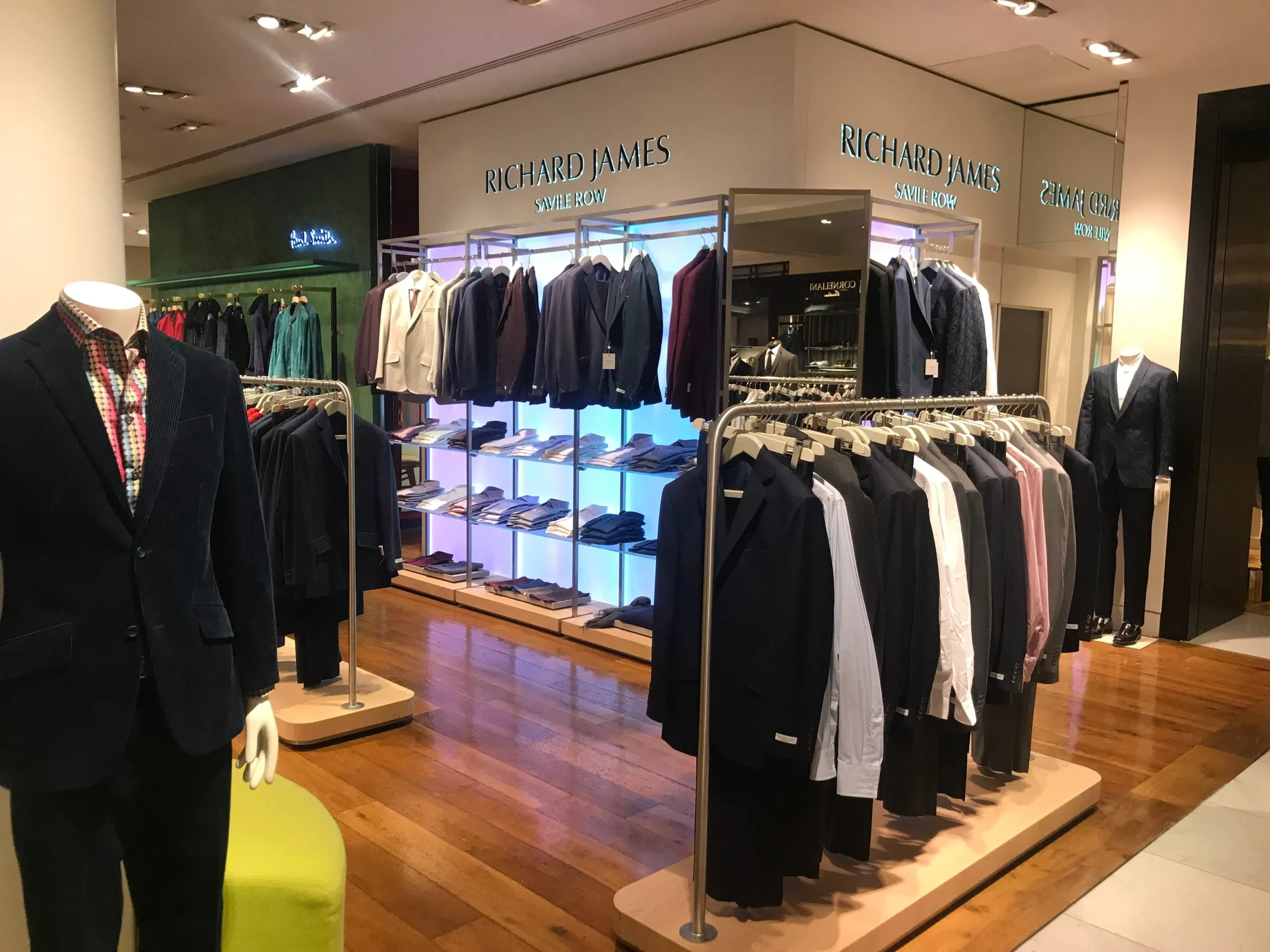 Richard James concession with suits on rails and backlit shirt shelving
