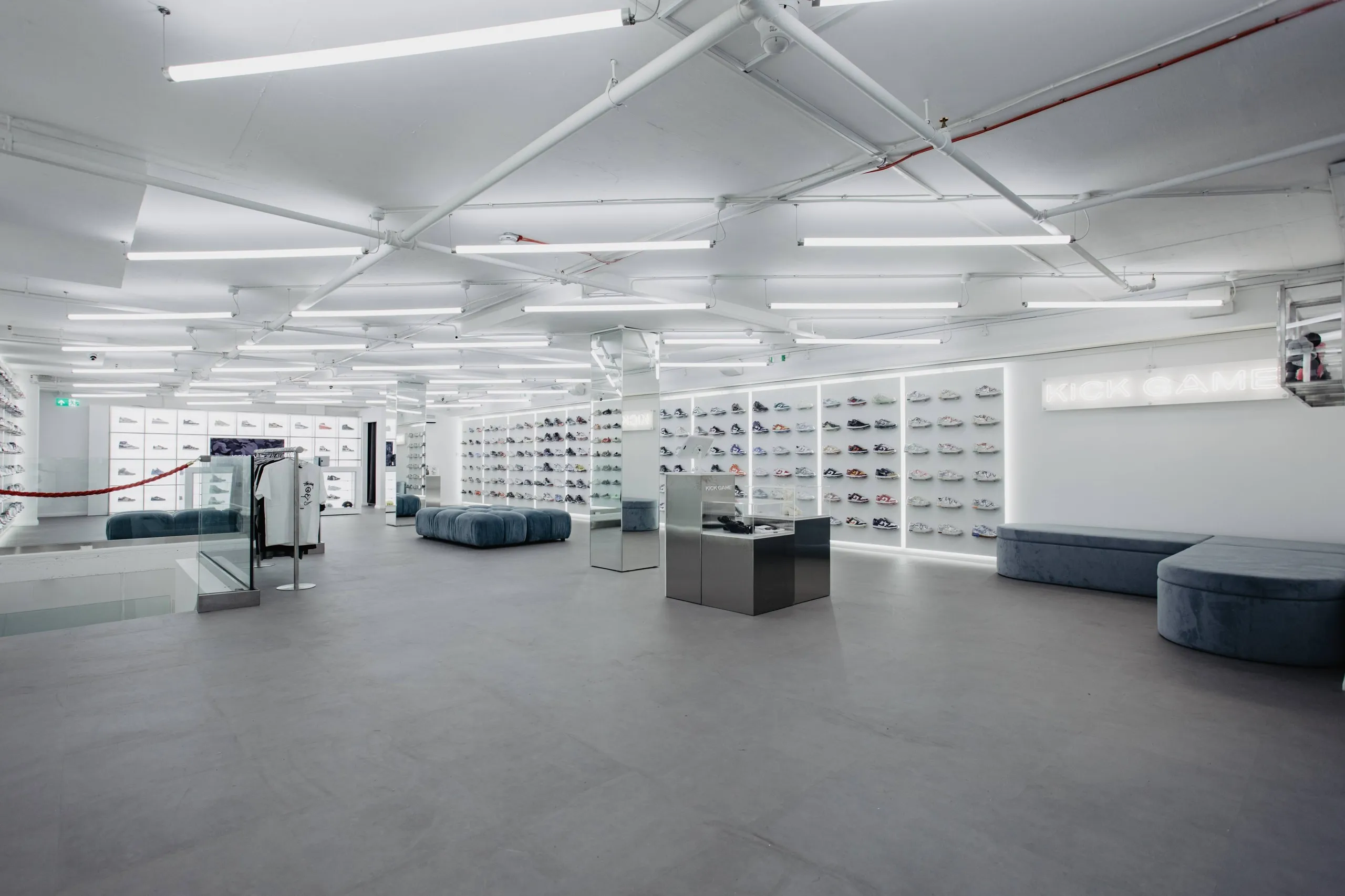 Kick Game store with grey seating, exposed ceiling and lit trainer walls