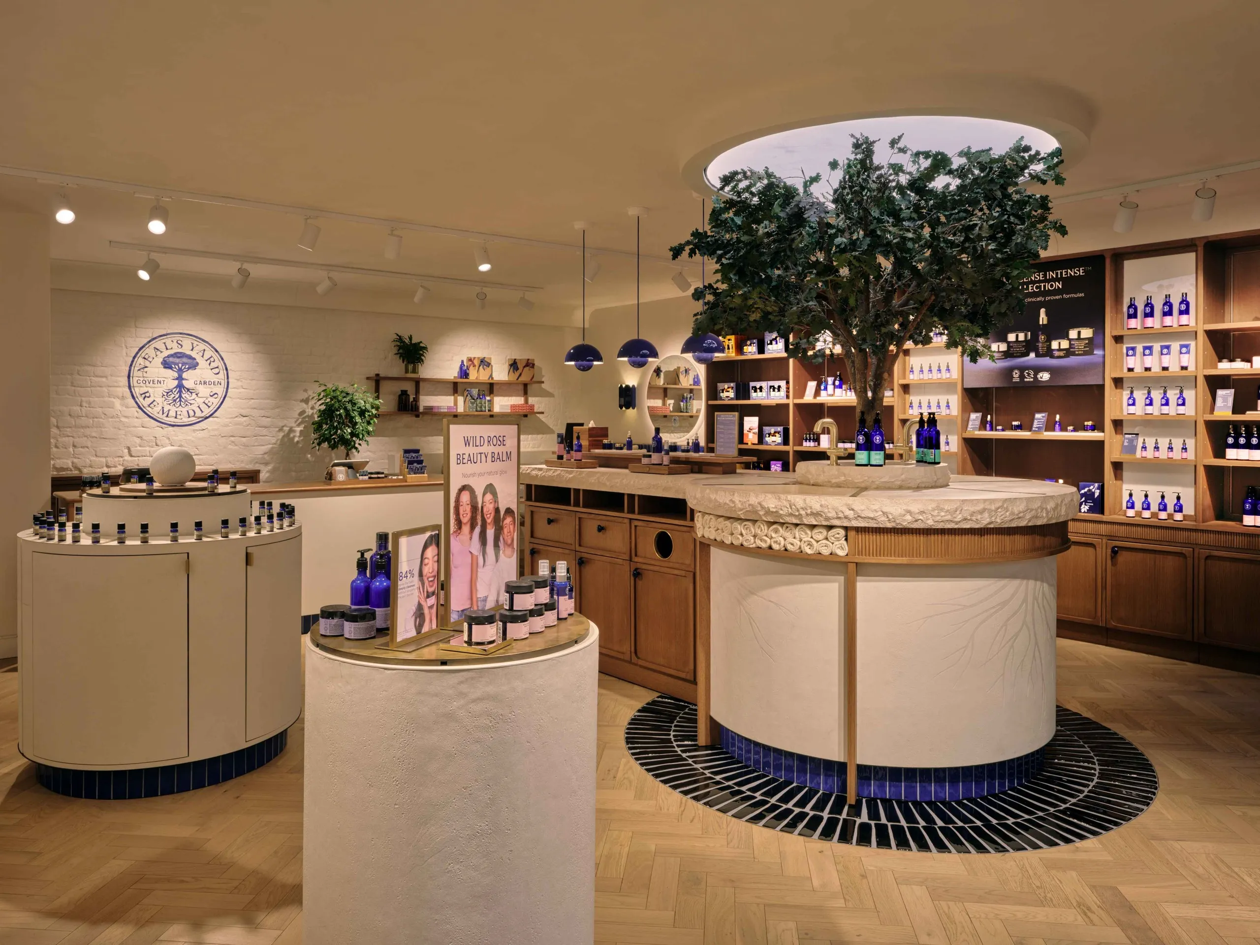 Neal's Yard Remedies store with round counters, a tree feature and blue tiled floor inlay