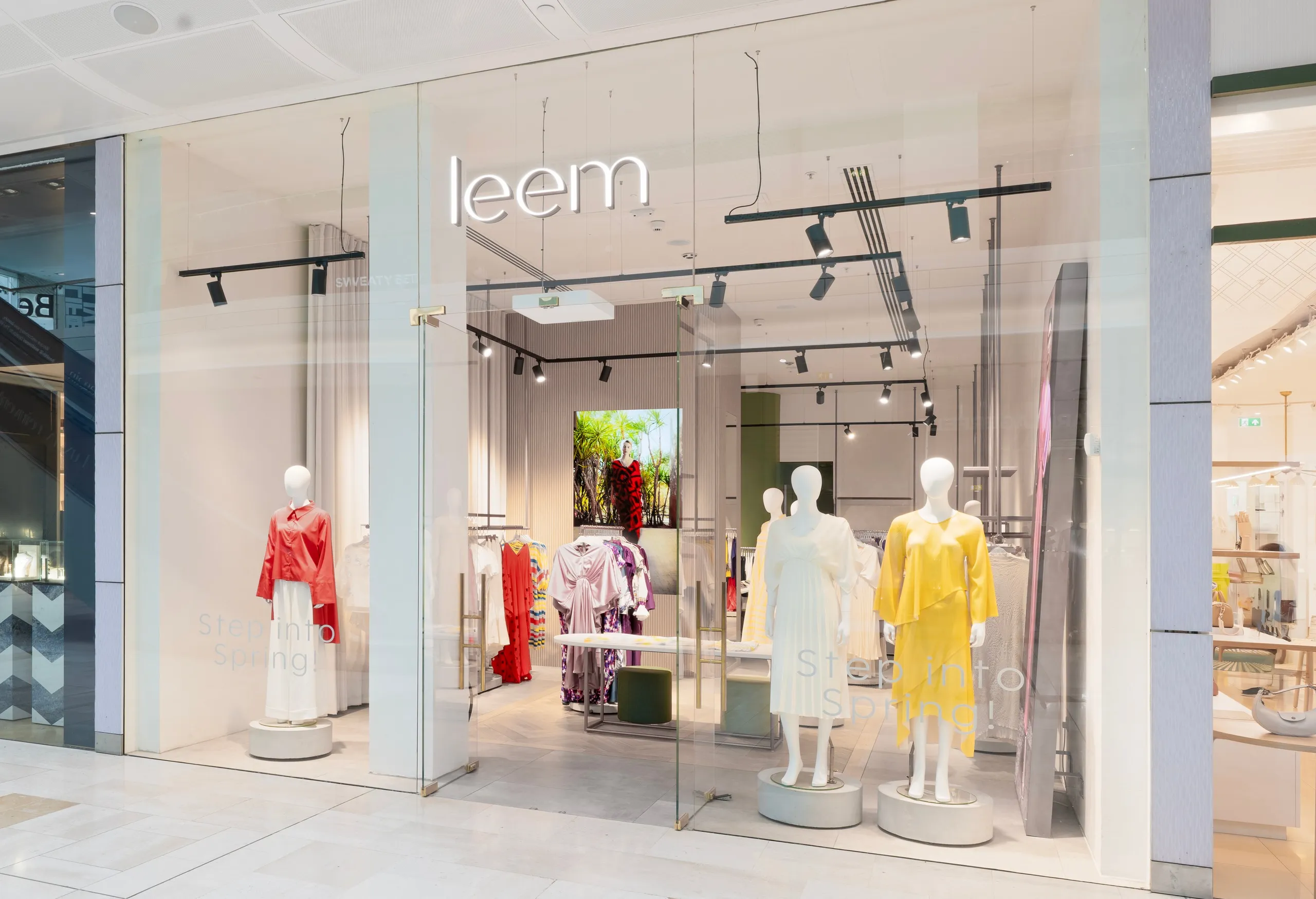 Handbag boutique with illuminated white shelving, herringbone floor and spiral staircase