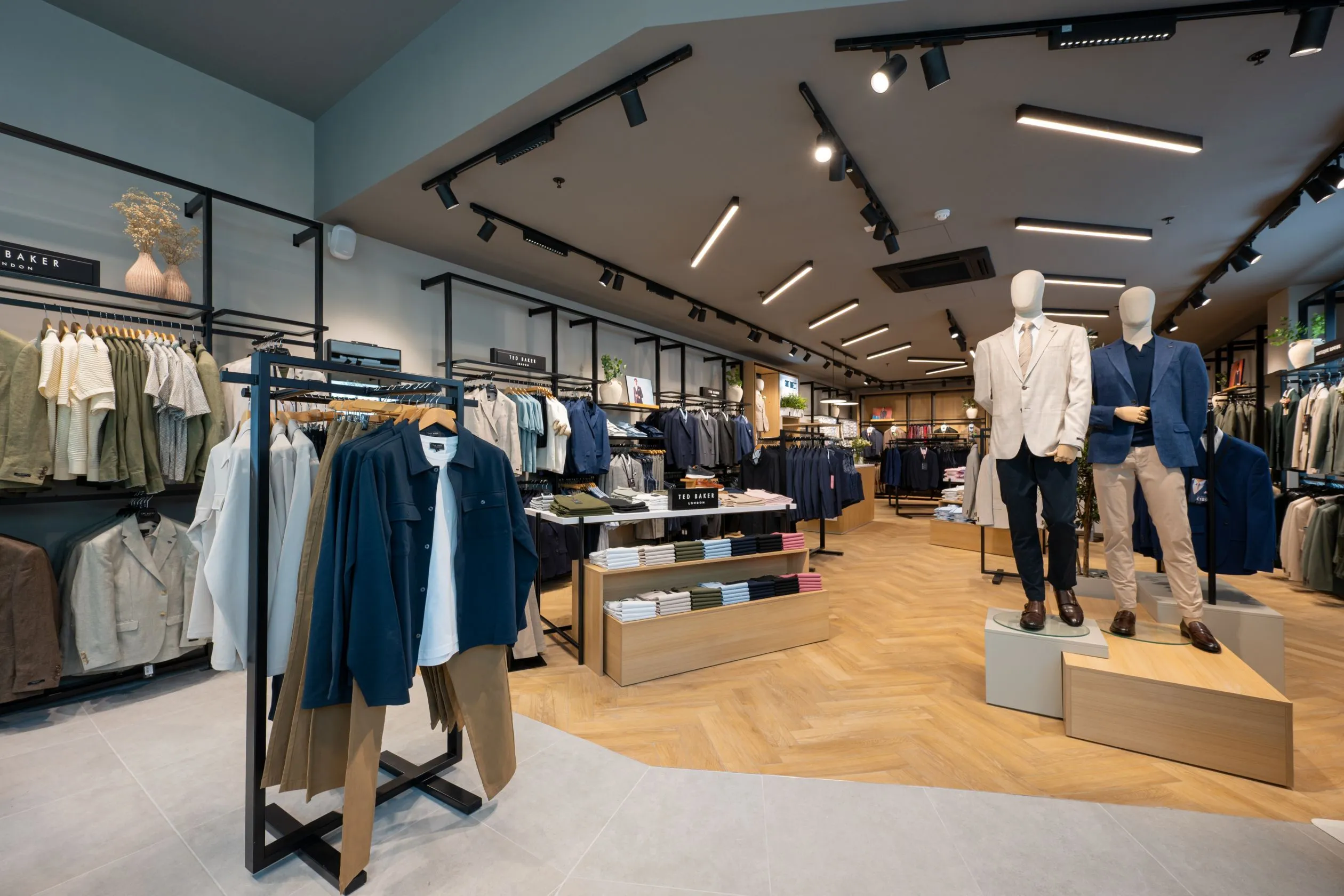 Suit Direct menswear floor with mannequins on plinths, black rails and track lighting