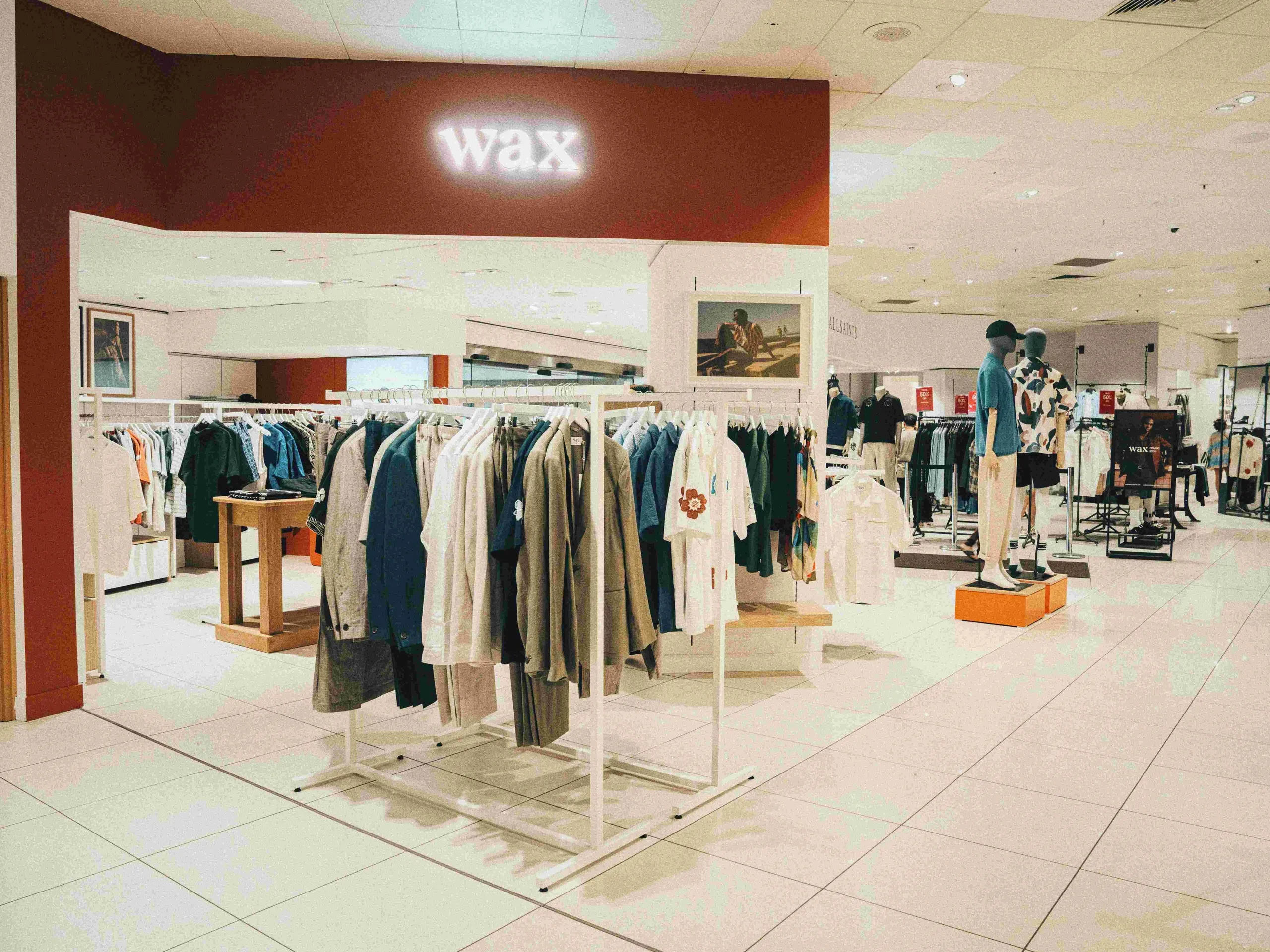 Wax London concession with clothing rails and a red feature wall in a department store