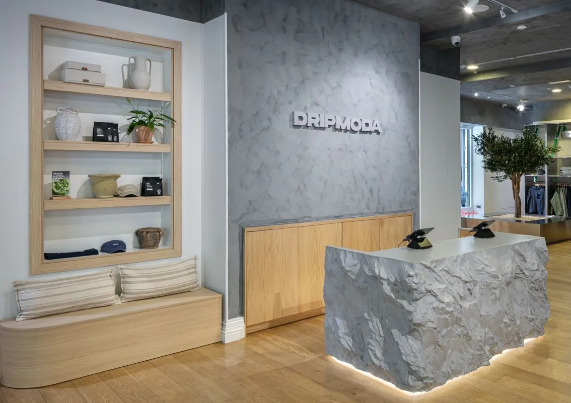 Drip Moda cash desk in textured stone, with oak display shelving and grey feature wall