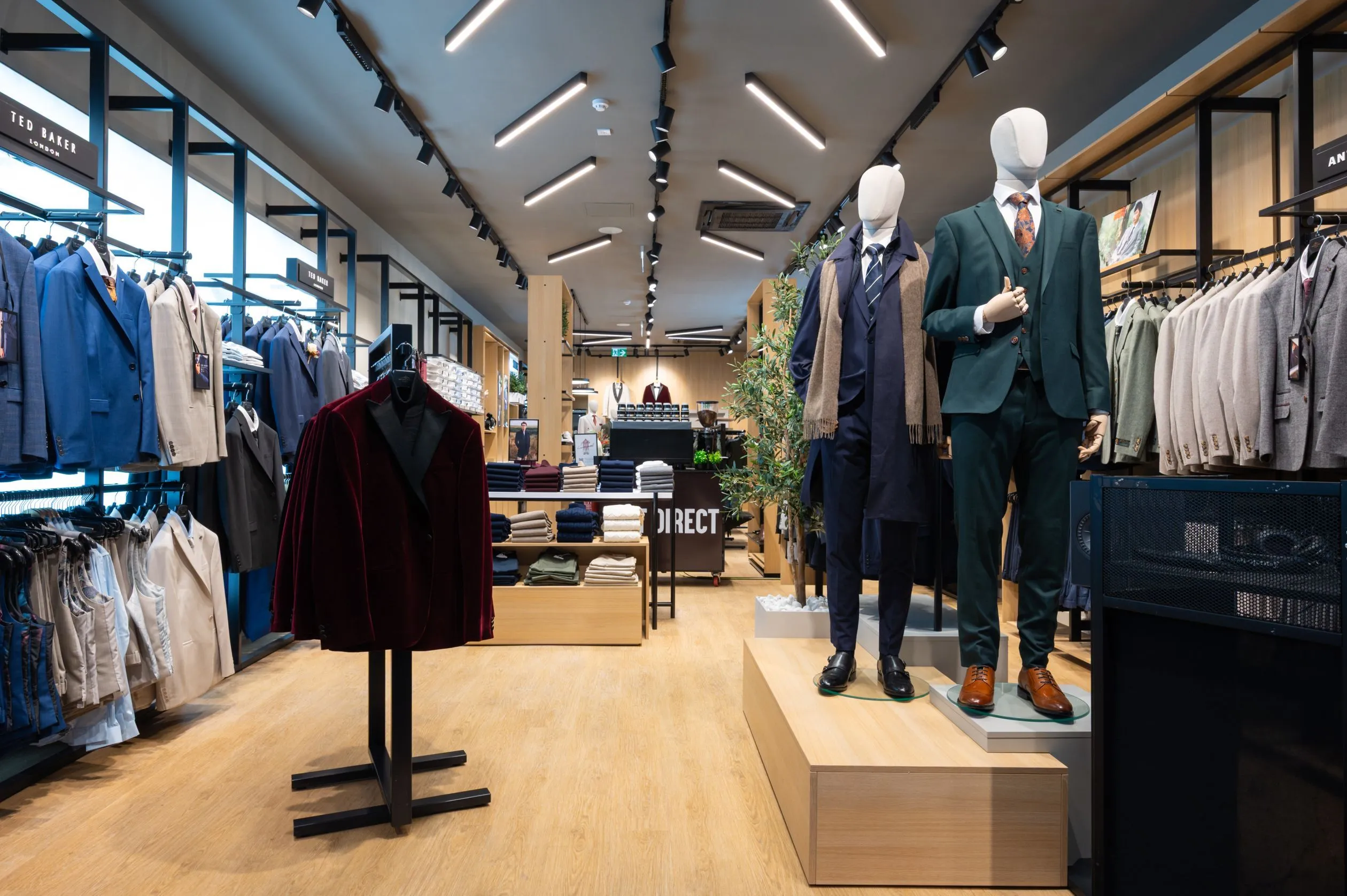 Suit Direct menswear store with suited mannequins, oak floor and linear lighting
