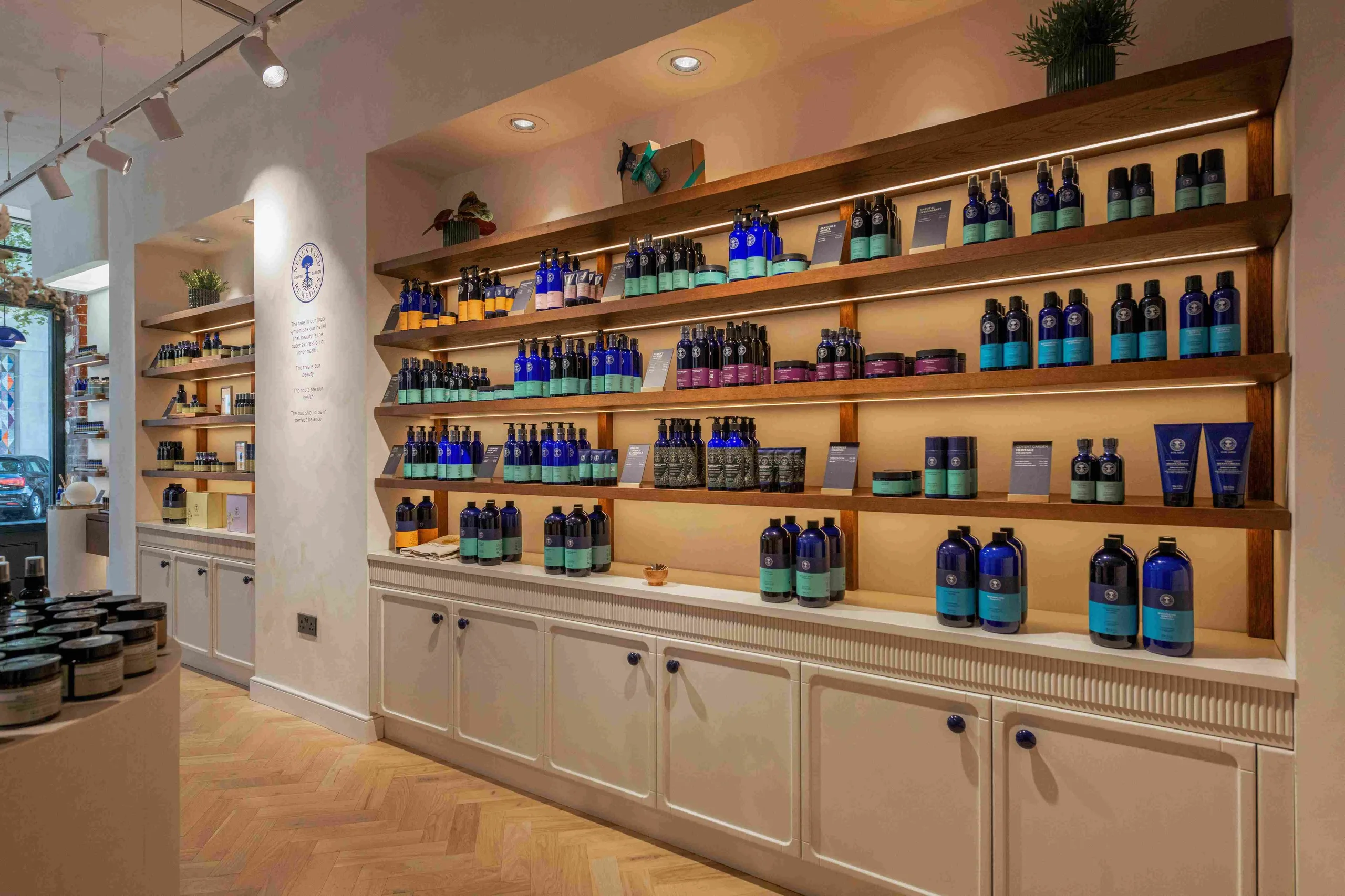 Neal's Yard Remedies illuminated timber shelving with blue bottle products