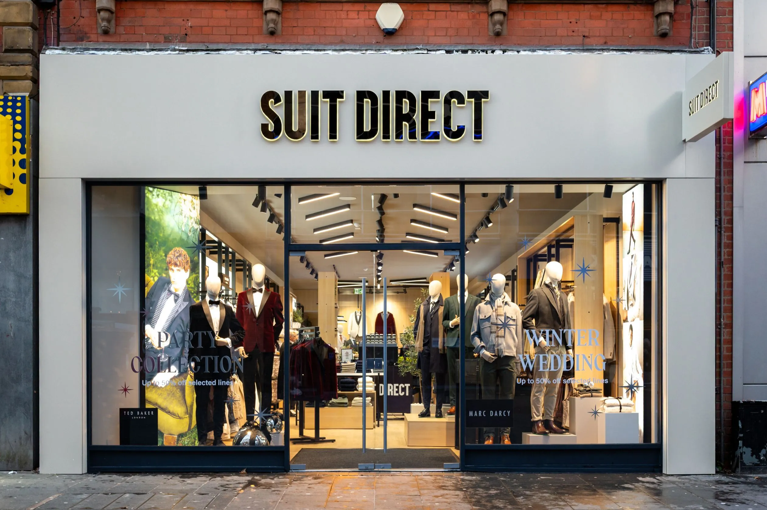 Suit Direct high street shopfront with suited mannequins in the window